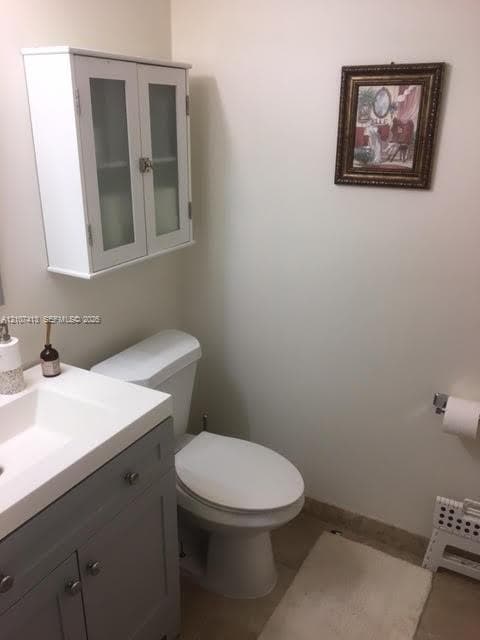 Grey vanity with a white countertop, wall-mounted white cabinetry with frosted glass doors, and a chrome-finish toilet paper holder