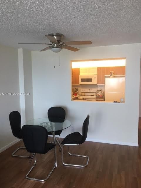 Wood-finish flooring, ceiling fan with integrated lighting, and built-in serving pass-through window with kitchen cabinetry and appliances