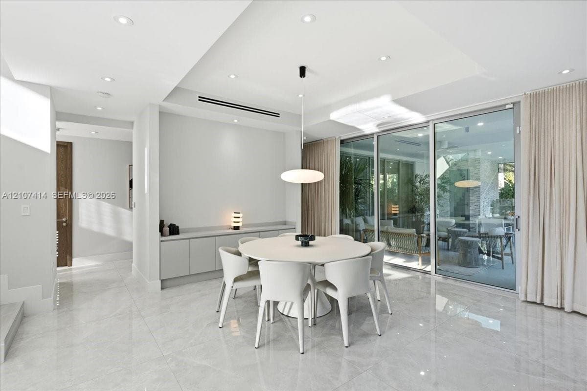 Polished stone-finish flooring, built-in wall cabinetry, recessed ceiling lighting, a modern pendant light fixture, and floor-to-ceiling sliding glass doors