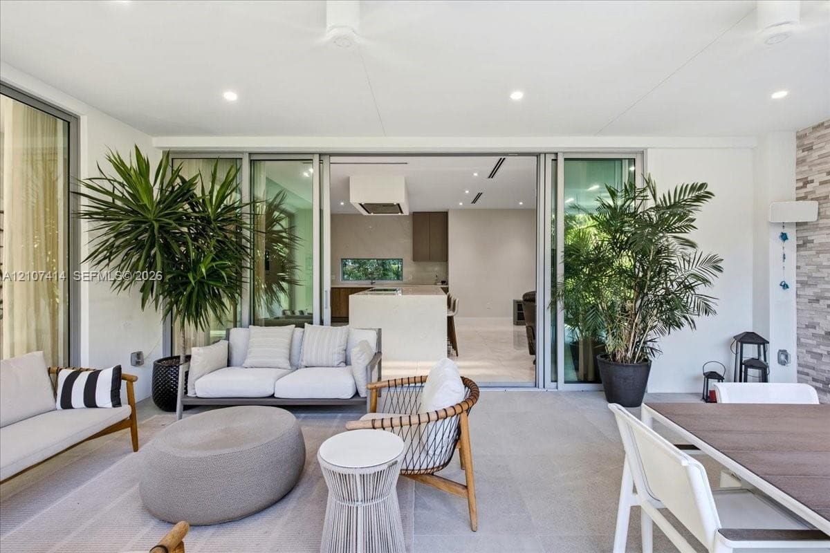 Covered patio featuring large-format stone-finish flooring, recessed ceiling lighting, and expansive floor-to-ceiling multi-panel sliding glass doors with thin-profile frames