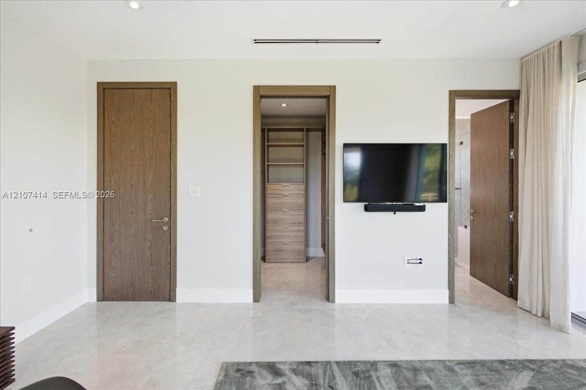 Interior space featuring large-format stone flooring, recessed lighting, and solid wood-finish doors