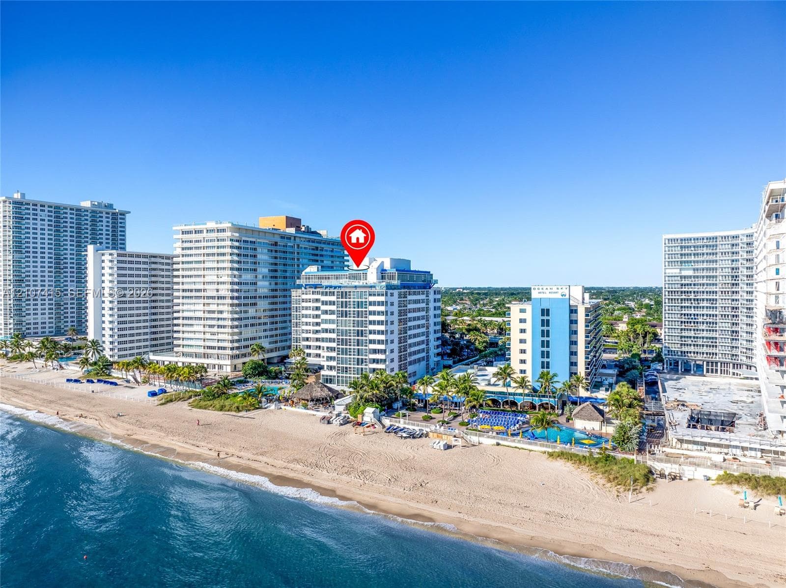 Mid-rise coastal residential structure featuring glass-paneled balconies and direct proximity to the shoreline