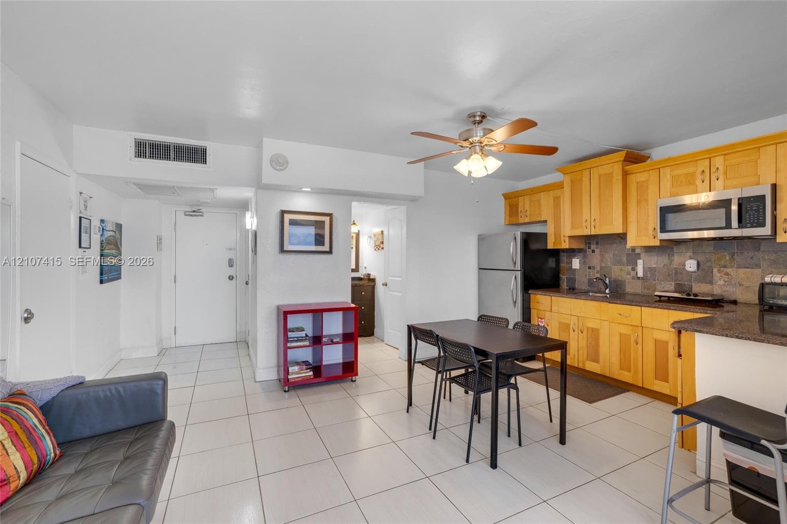 Kitchen featuring light-finish cabinetry, stone tile backsplash, and integrated stainless steel microwave