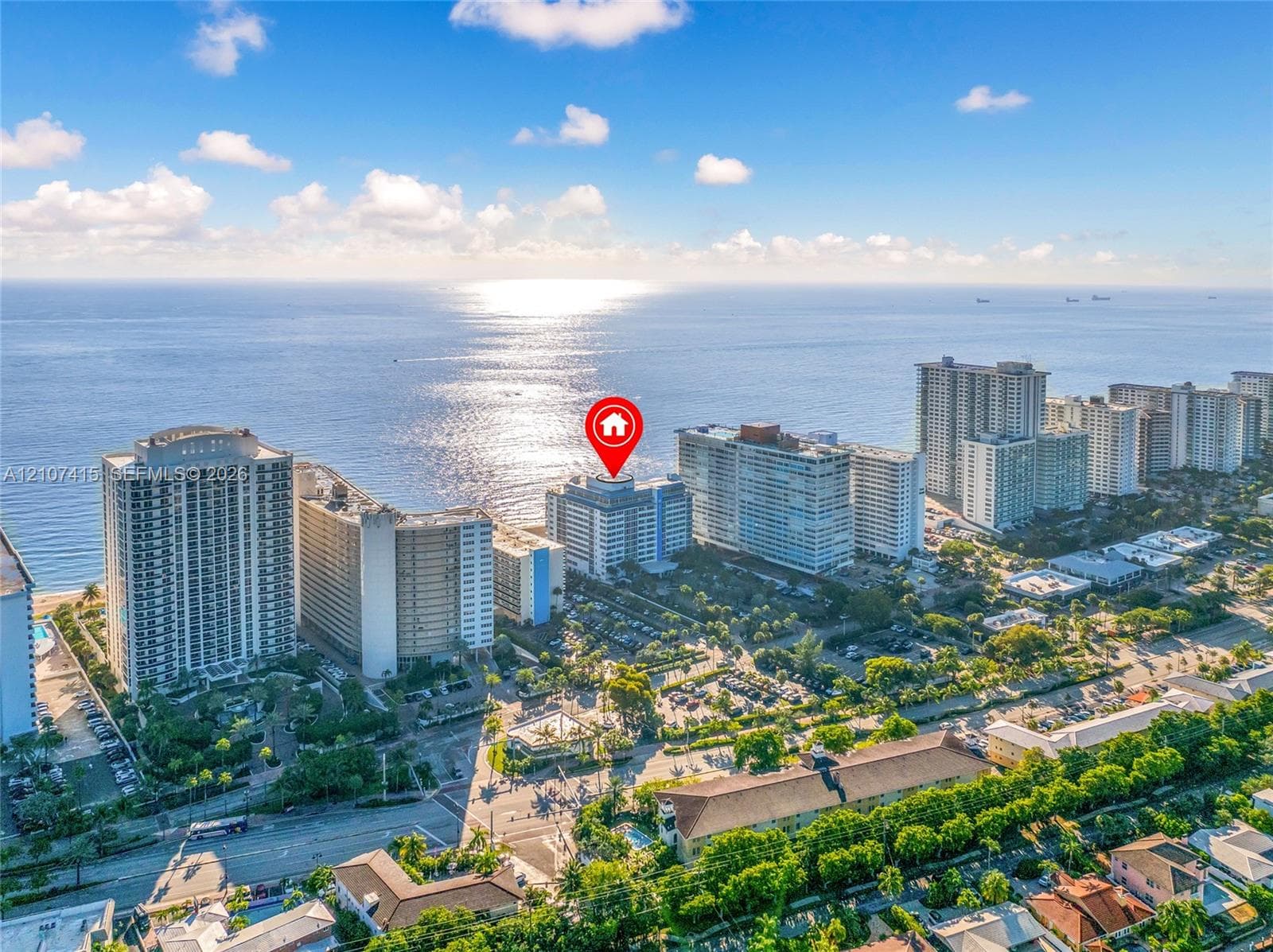 Aerial perspective of a coastal high-rise property featuring direct proximity to the oceanfront and a sprawling beach shoreline