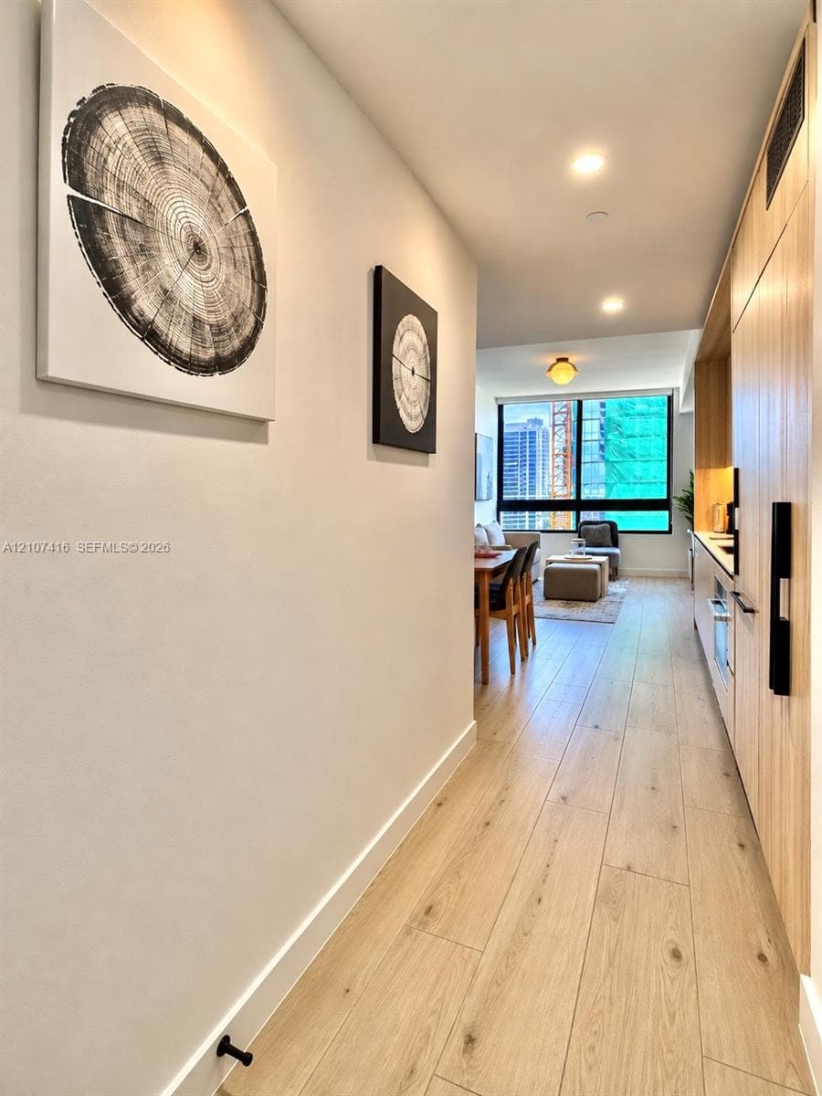 Wood-finish flooring, full-height flat-panel cabinetry, recessed ceiling lighting, and floor-to-ceiling windows