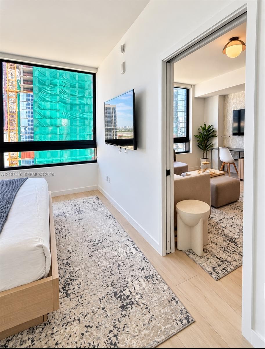 Floor-to-ceiling windows with black frames, wood-finish flooring, sliding glass door, and flush-mount globe lighting