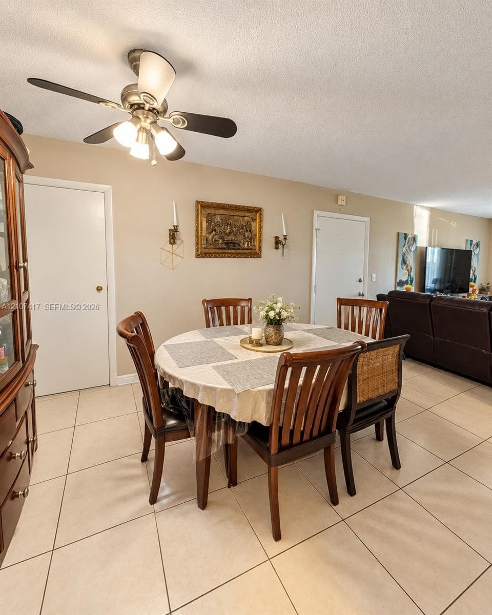Light-toned tile flooring, neutral wall paint, three-light ceiling fan with integrated glass shades, and dual wall-mounted sconces