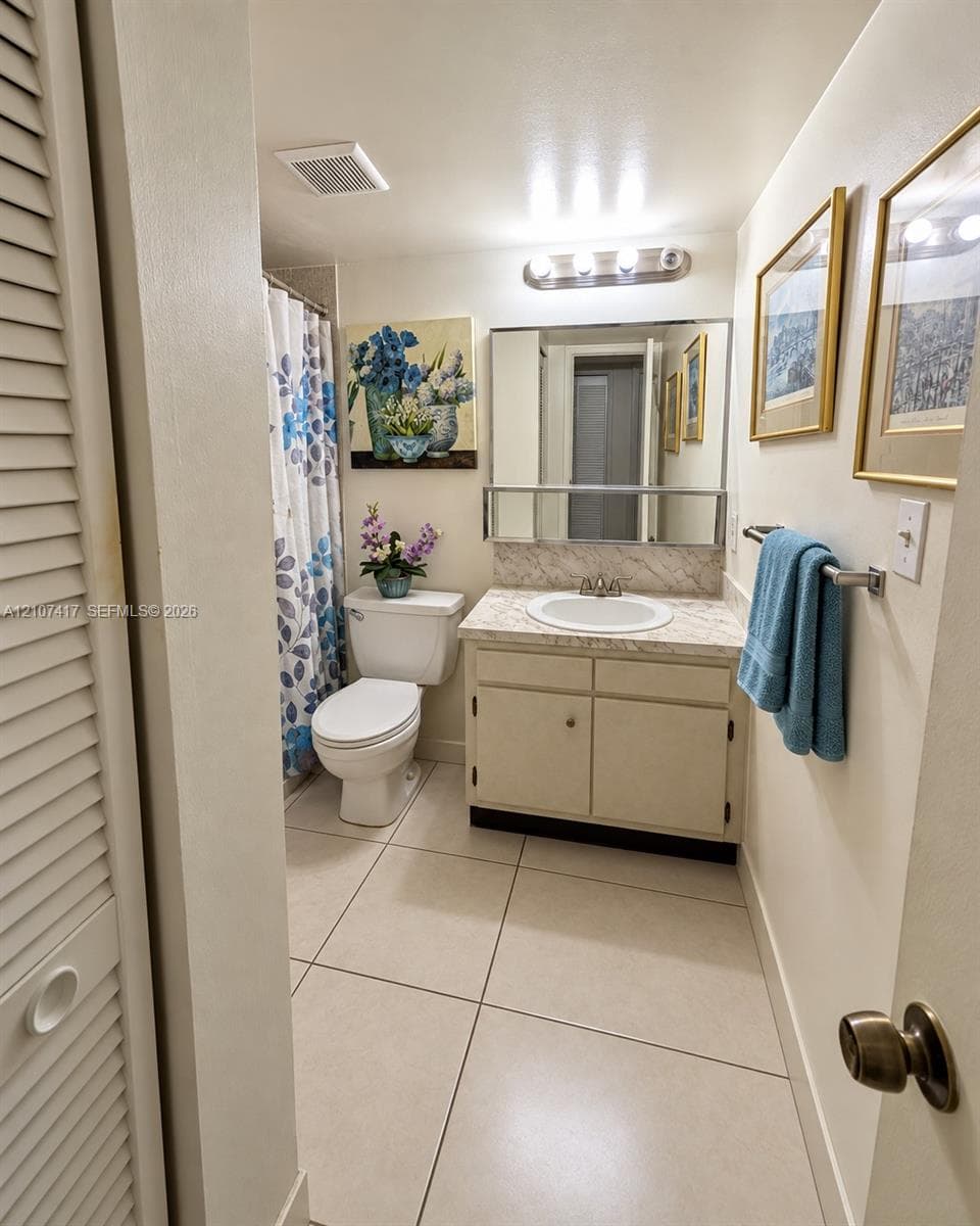 Bathroom featuring large-format tile flooring, vanity with a stone-finish countertop, integrated basin, and a wall-mounted medicine cabinet with a mirror