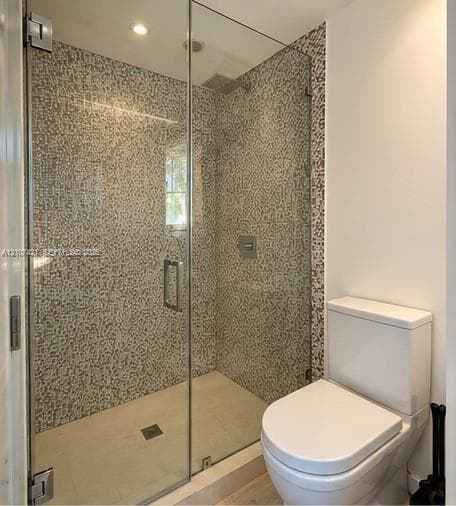 Walk-in shower featuring a frameless glass door, full-height mosaic tile surround, rainfall shower head, and recessed lighting