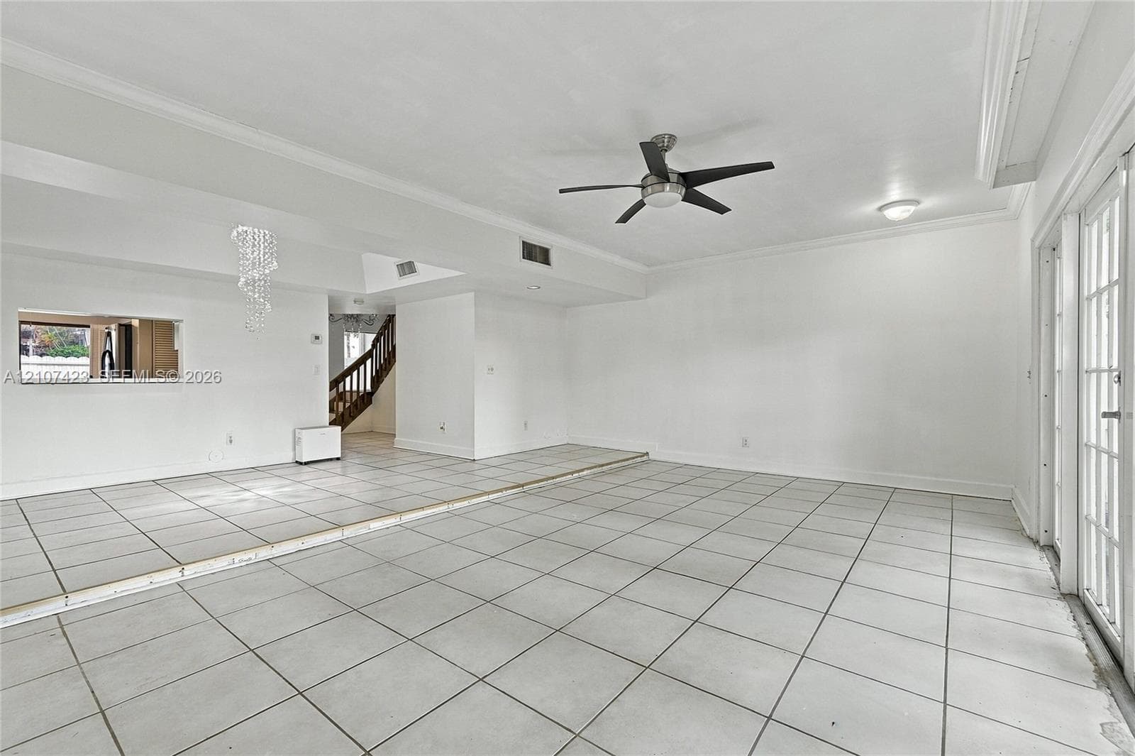 Sunken living area featuring large-format tile flooring, a tiered floor plan, a ceiling fan, and multi-pane glass doors