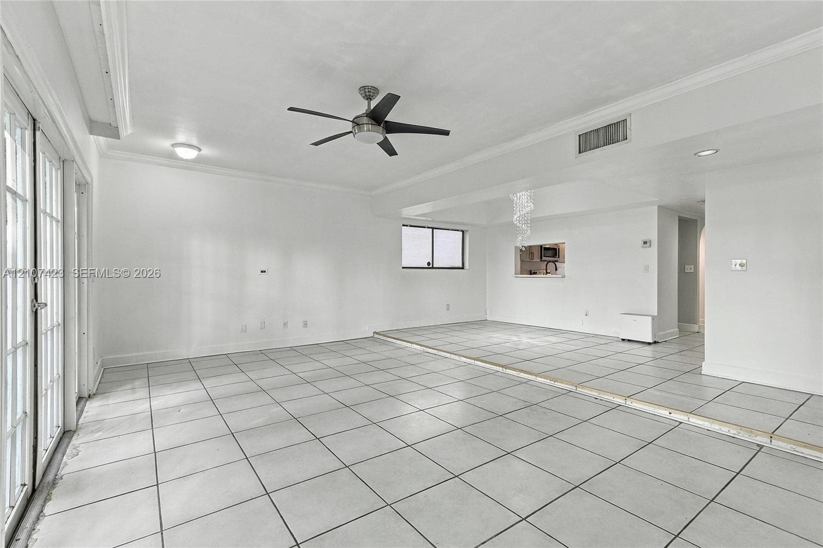 Interior space featuring large-format ceramic floor tile, crown molding, a multi-blade ceiling fan with integrated lighting, recessed lighting, and a multi-pane glass door system