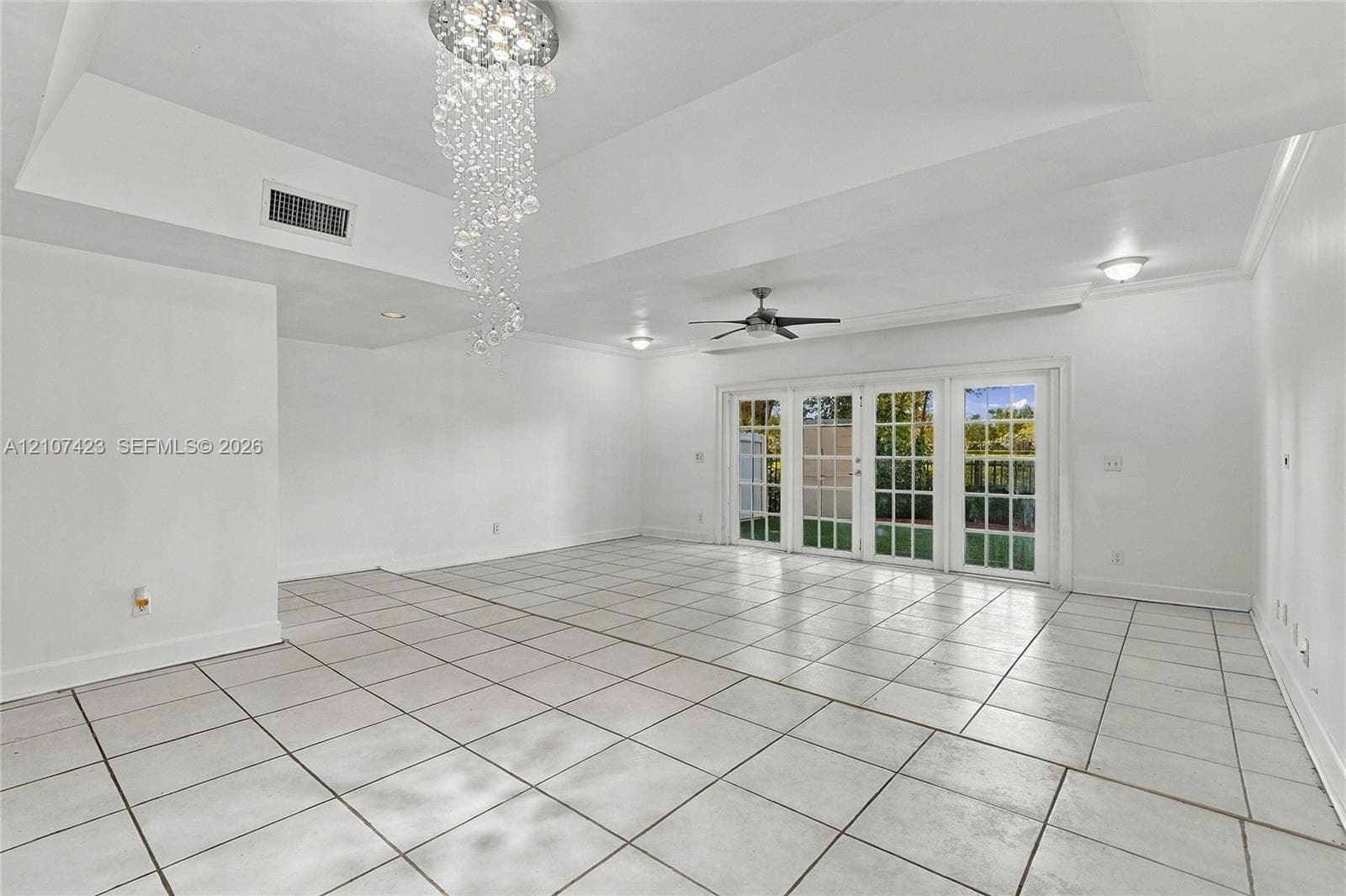 Tray ceiling with recessed lighting, crystal-style chandelier, ceramic tile flooring, and multi-panel French doors