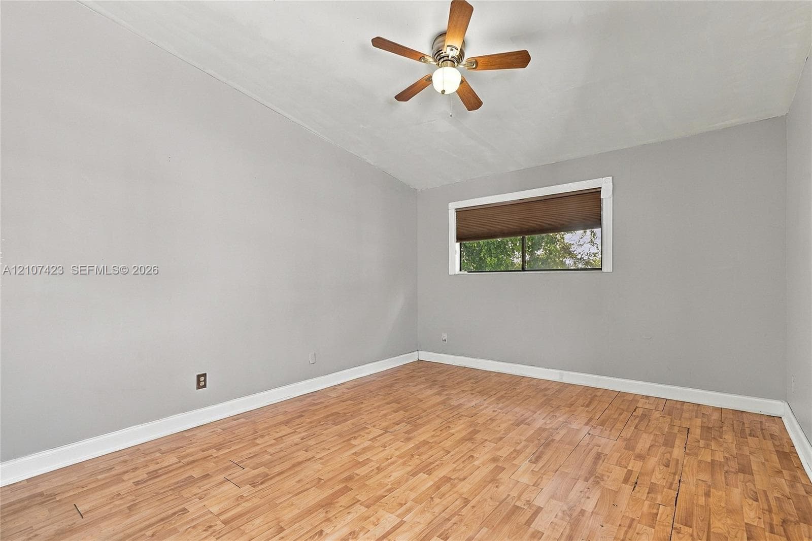 Room featuring wood-finish flooring, neutral wall paint, and a ceiling-mounted fan with integrated light fixture