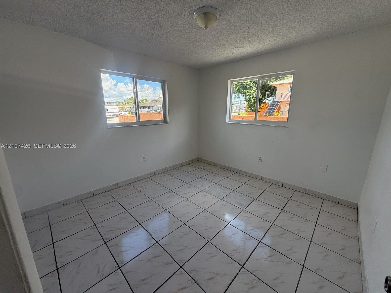 Neutral-toned walls paired with large-format tile flooring and dual sliding windows providing natural light