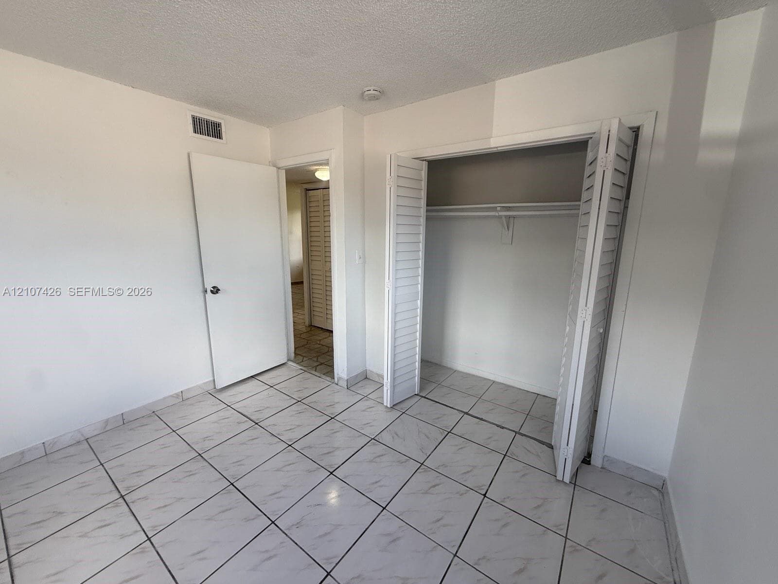 Interior room featuring diagonal-pattern tile flooring, a closet with bi-fold louvered doors, and a solid-core interior swing door