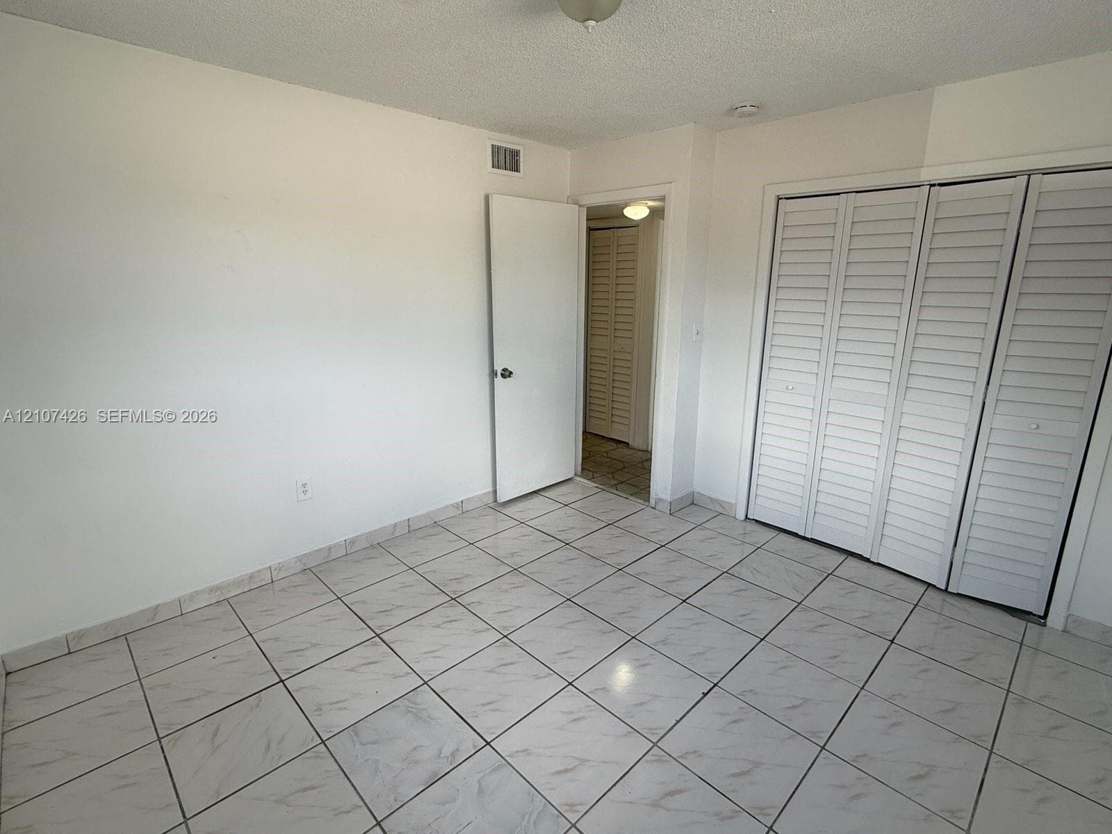 Ceramic tile flooring throughout with louvered bi-fold closet doors and neutral wall finishes