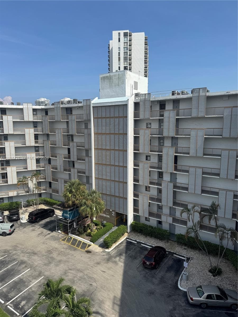 Multi-story residential complex featuring geometric facade detailing, exterior-facing balconies, and dedicated surface parking