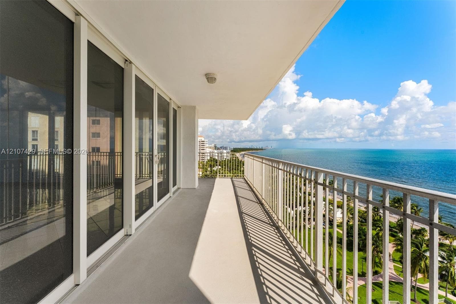 Expansive living area featuring polished tile flooring, floor-to-ceiling sliding glass doors, and a balcony with an ocean backdrop