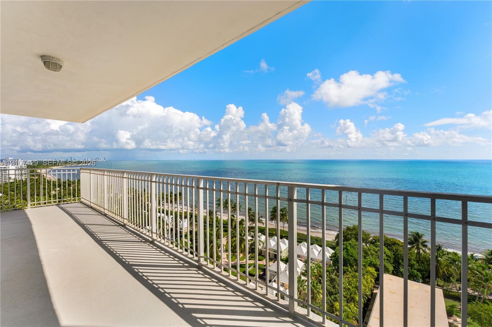 Spacious room featuring light-toned tile flooring, floor-to-ceiling glass sliding doors, and a metal balcony railing