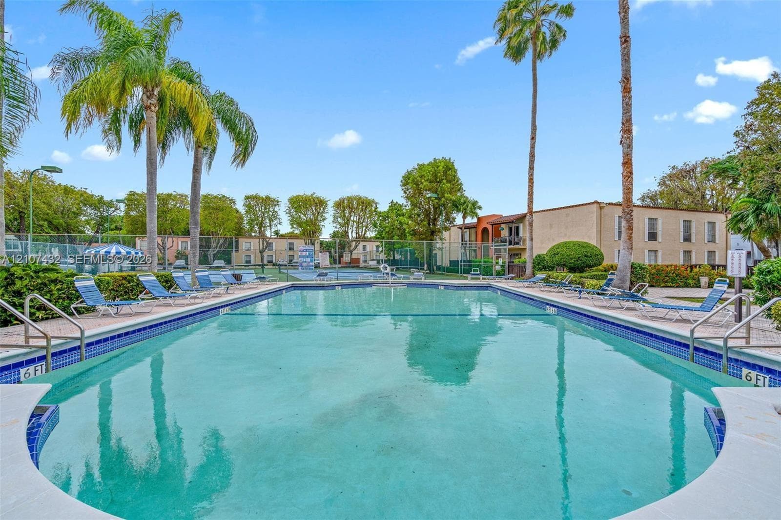 Swimming pool with tile edging, metal safety rails, and perimeter fencing