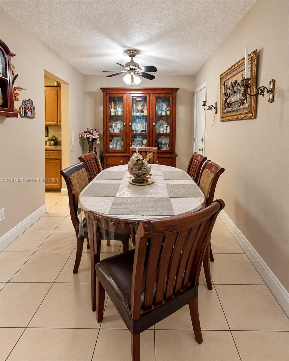 Neutral tile flooring, ceiling-mounted paddle fan with integrated light fixture, and wall-mounted candle-style sconces