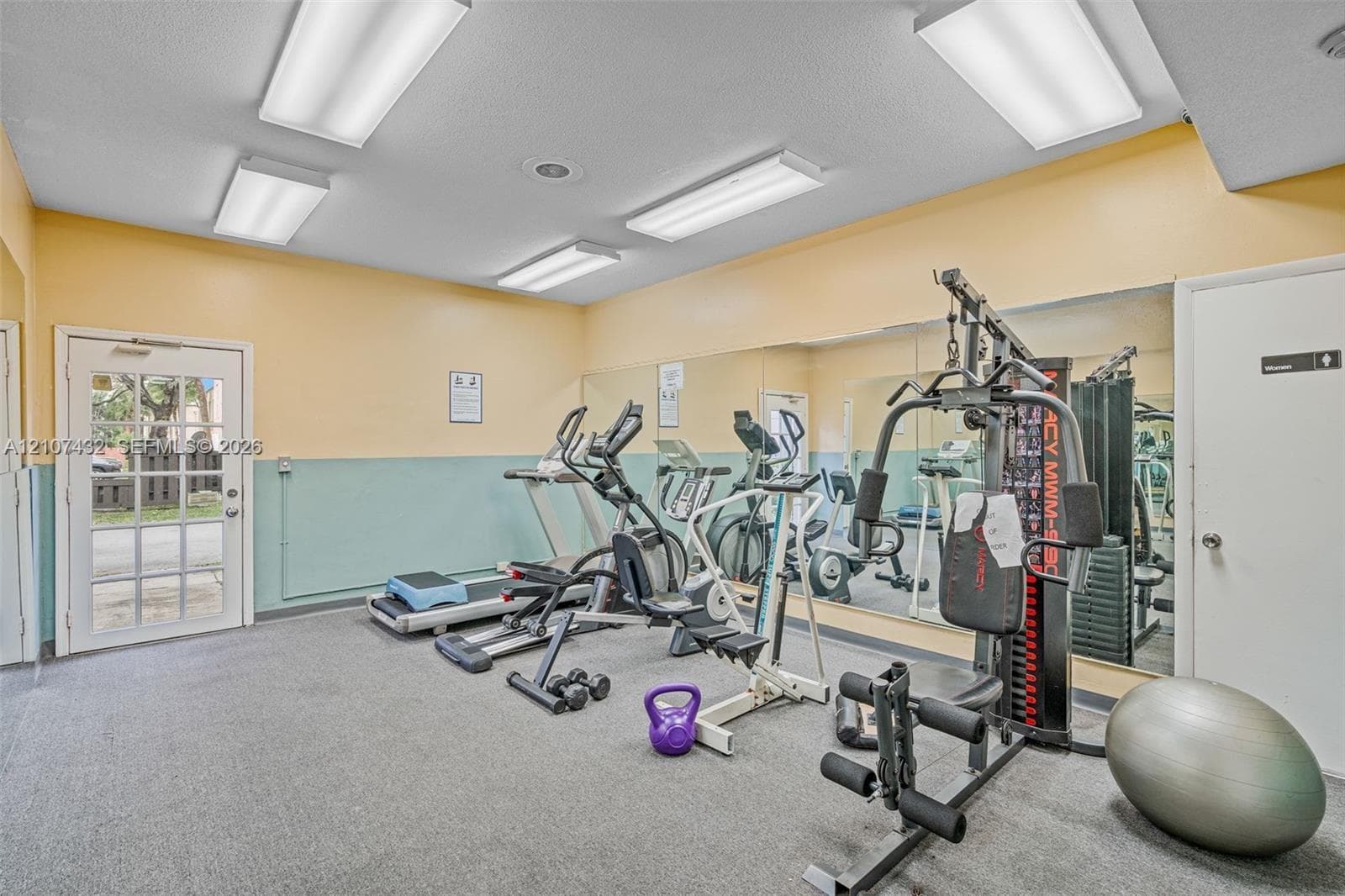 Fitness space featuring full-wall mirrors, recessed lighting, and a glass-panel exterior door
