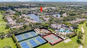 Aerial perspective featuring multiple tennis courts, a swimming pool, and a central lake