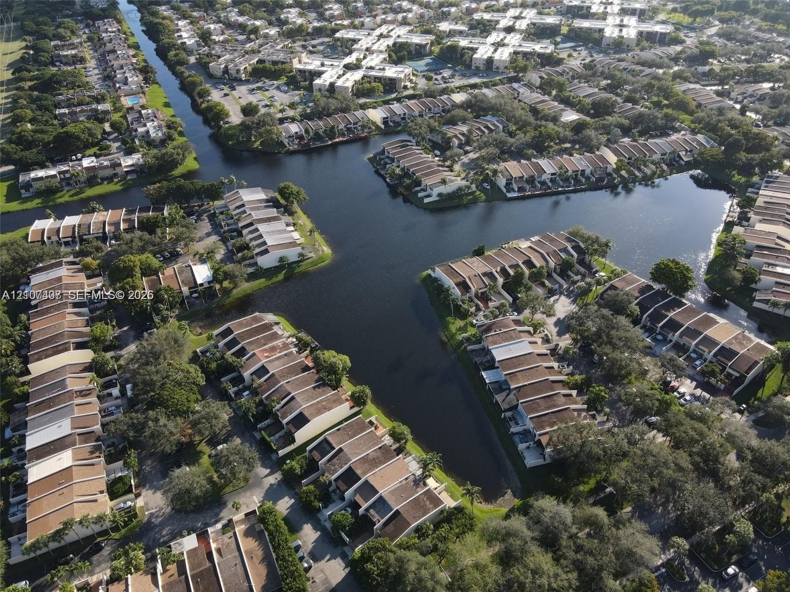Aerial perspective of multi-family structures situated along a canal system featuring mature trees and established landscaping