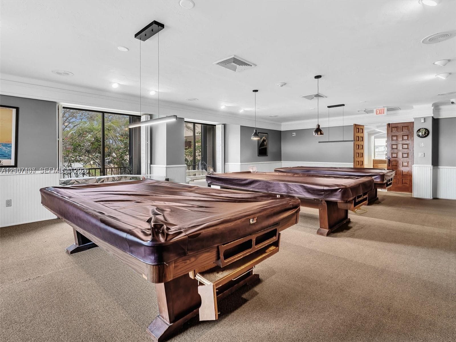 Recreation space featuring wall-to-wall carpeting, beadboard wainscoting, recessed ceiling lighting, industrial-style pendant light fixtures, and expansive sliding glass doors