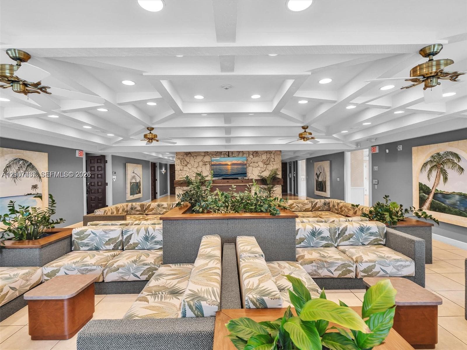 Coffered ceiling with integrated recessed lighting, stone-clad accent wall, and multiple ceiling fans