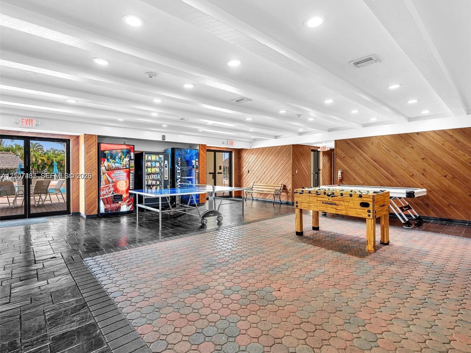 Common area featuring a coffered ceiling with recessed lighting, diagonally-installed wood-paneled walls, and hexagonal paver flooring