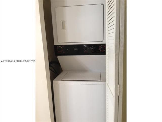 Stacked laundry center featuring a white top-load washer and front-load dryer enclosed by louvered bi-fold doors