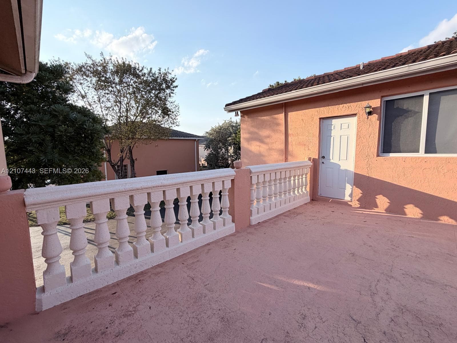 Stucco exterior balcony with decorative concrete balustrade, integrated wall-mounted lighting, and exterior access door