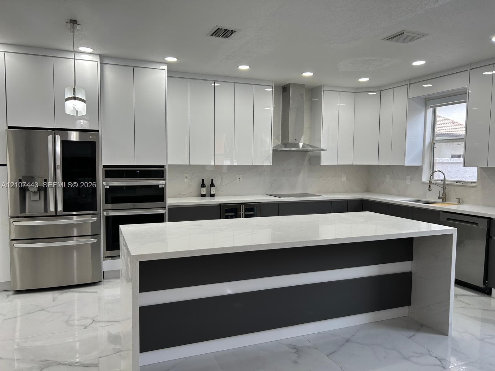 Kitchen featuring high-gloss white cabinetry, a center island with stone-finish countertops, stainless steel appliances, a chimney-style range hood, and large-format polished tile flooring