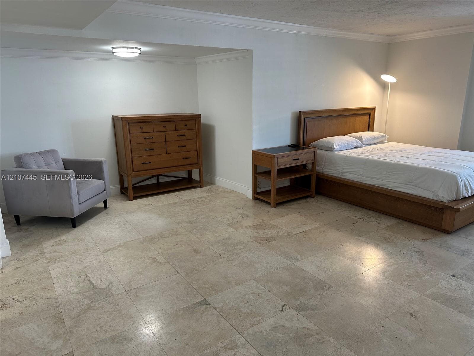 Spacious interior featuring large-format stone tile flooring, crown molding, and recessed ceiling lighting