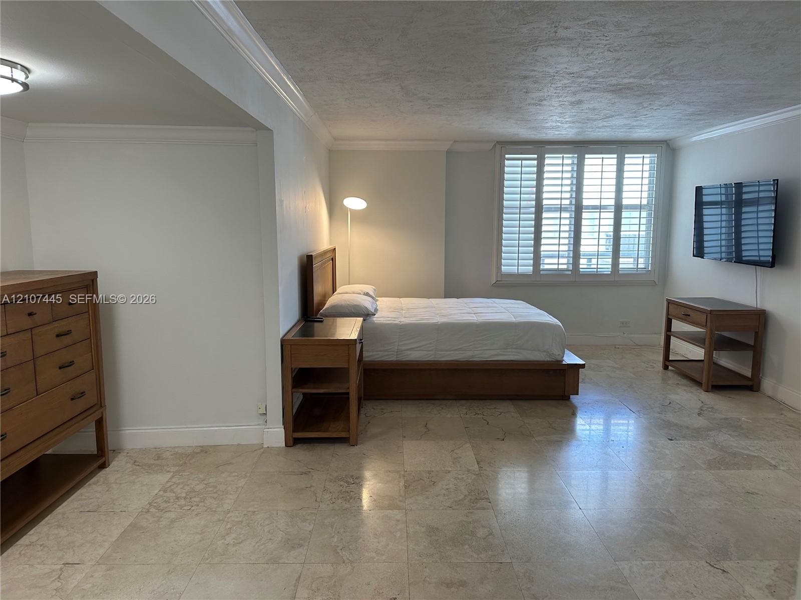 Neutral stone flooring, plantation shutters, crown molding, and recessed lighting