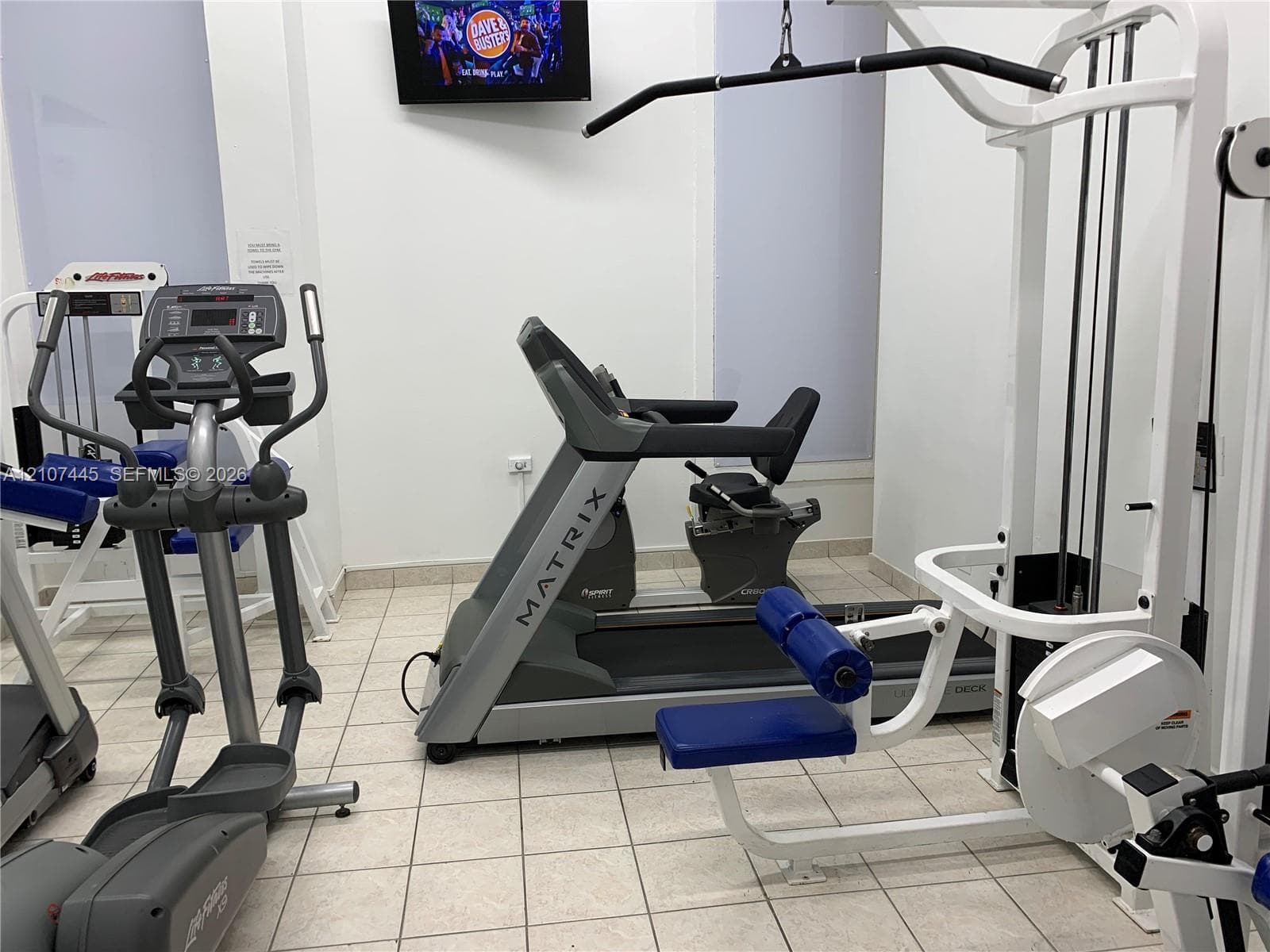 Fitness space featuring white walls and neutral ceramic tile flooring