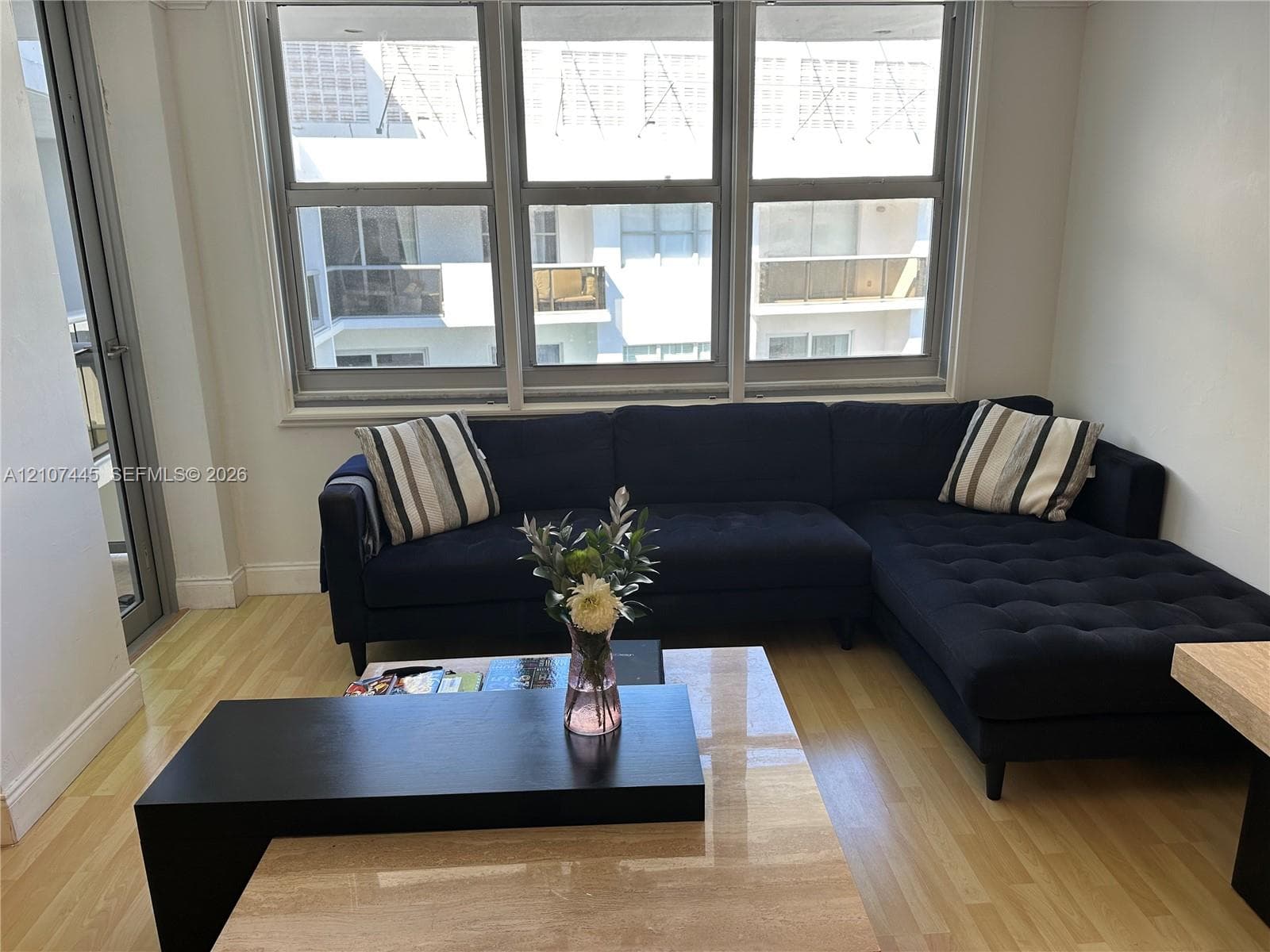 Floor-to-ceiling windows, light-toned wood-finish flooring, and glass-paneled entry door