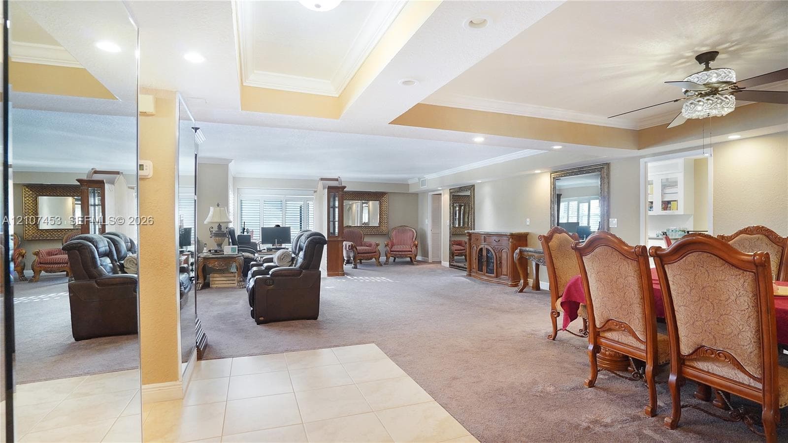 Open-concept interior featuring recessed tray ceilings, large-format tile flooring, wall-to-wall carpeting, and recessed lighting