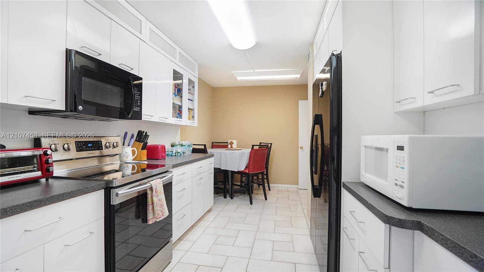 Kitchen featuring white cabinetry, solid-surface countertops, tile flooring, and stainless steel appliances
