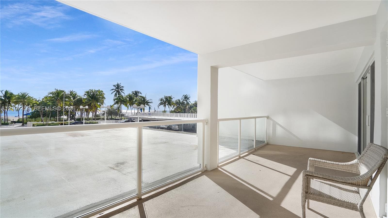 Covered outdoor terrace featuring concrete flooring and a white powder-coated railing with glass panel inserts