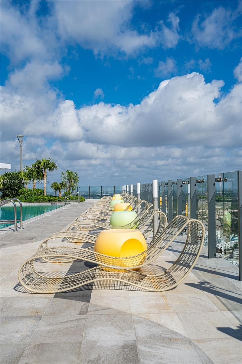 Rooftop swimming pool area featuring stone tile decking and a glass panel railing