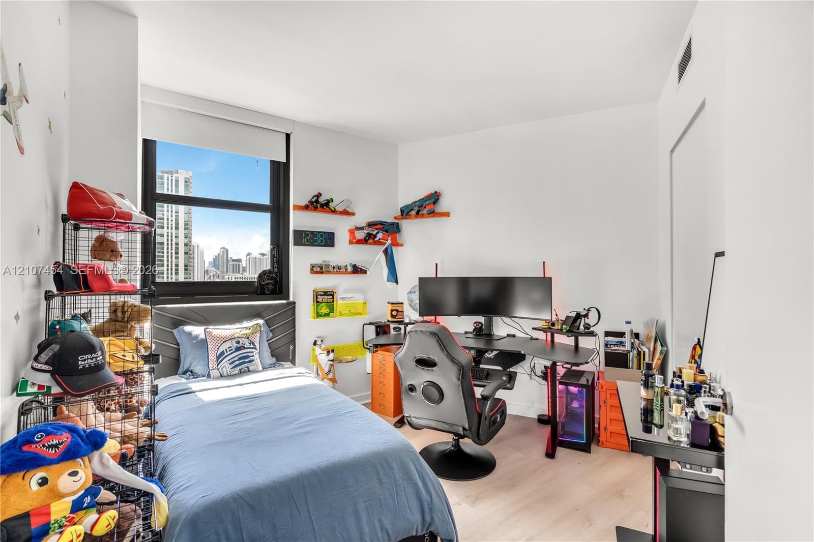 Bedroom featuring light-tone wood-finish flooring, a large window with black framing, and neutral wall paint