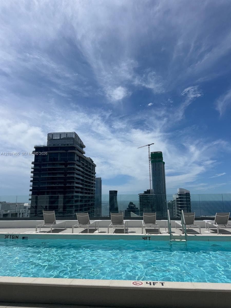 Rooftop terrace featuring a rectangular swimming pool, expansive tile deck, and glass perimeter railing