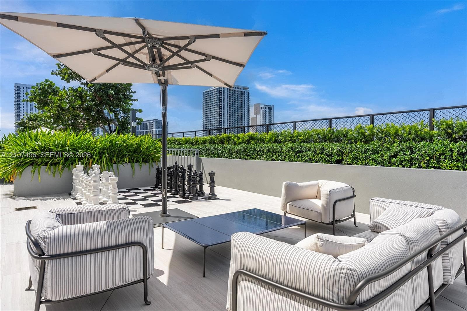 Rooftop terrace featuring large-format tile flooring, a concrete perimeter wall, integrated garden planter boxes, and a metal wire fence