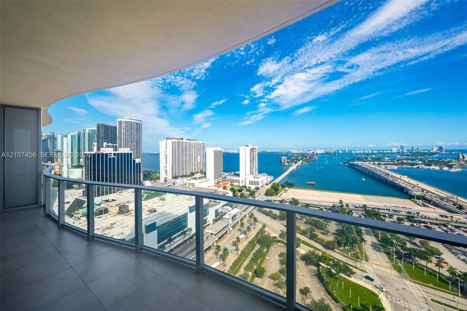 Curved balcony featuring large-format porcelain tile flooring and a sleek glass-panel railing