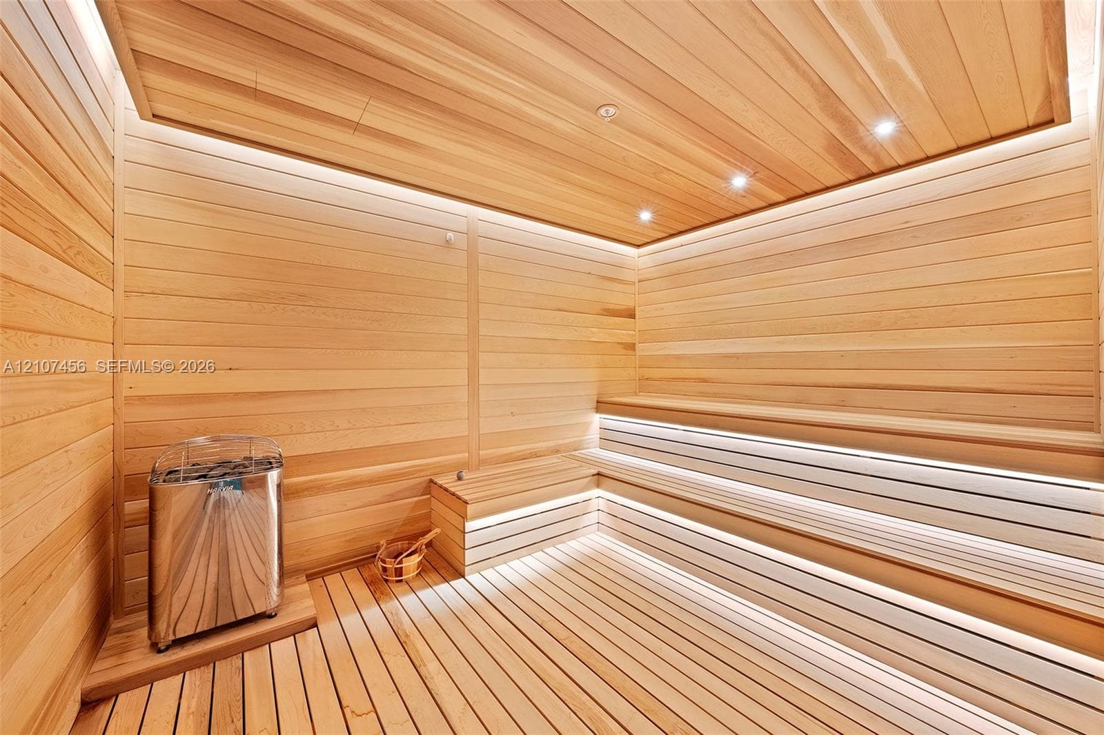 Sauna featuring tongue-and-groove wood paneling, multi-level built-in bench seating, recessed lighting, integrated LED strip lighting, and a stainless steel heater