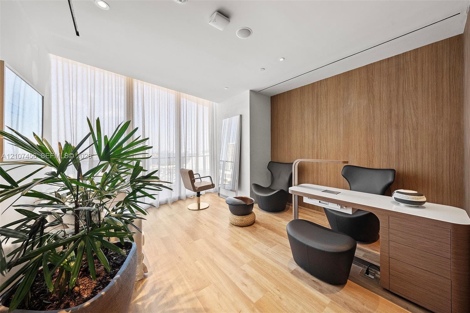 Floor-to-ceiling windows with sheer drapery, wood-finish flooring, wood-panel accent wall, recessed ceiling lighting, and built-in cabinetry