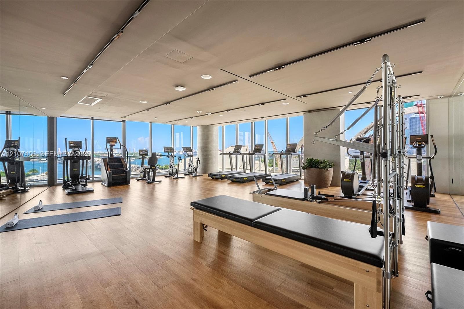 Fitness facility featuring floor-to-ceiling windows, wood-finish flooring, recessed lighting, and expansive wall mirrors