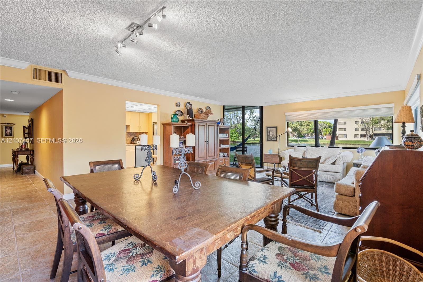 Open-concept interior featuring large-format tile flooring, multi-directional track lighting, and expansive windows